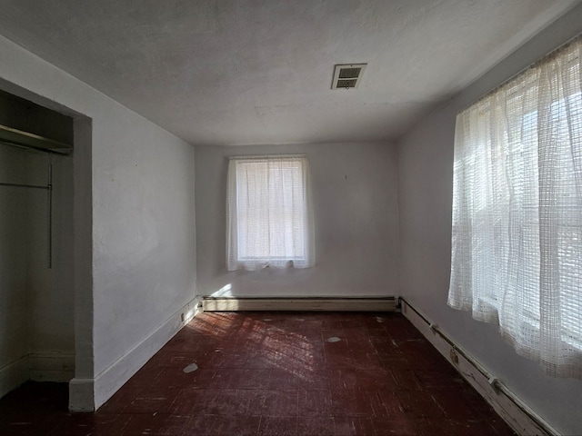 unfurnished room featuring a textured ceiling and baseboard heating