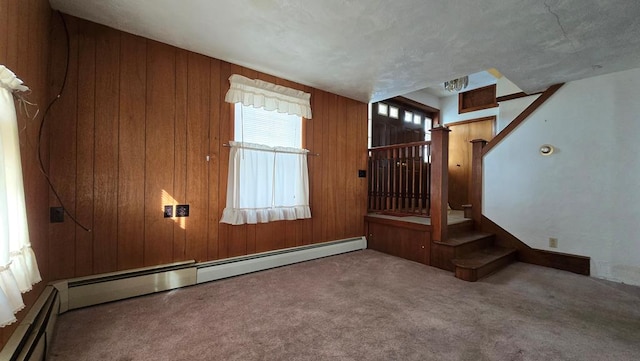 interior space with a baseboard heating unit, carpet floors, and wood walls