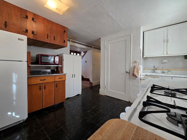 kitchen featuring white refrigerator, white cabinetry, and gas range oven