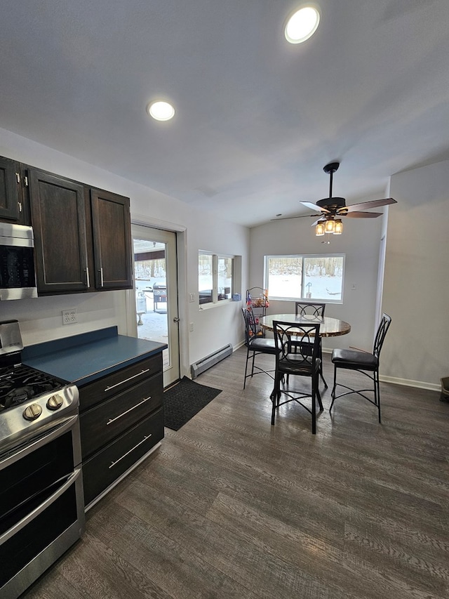 kitchen featuring lofted ceiling, dark hardwood / wood-style flooring, ceiling fan, baseboard heating, and stainless steel appliances