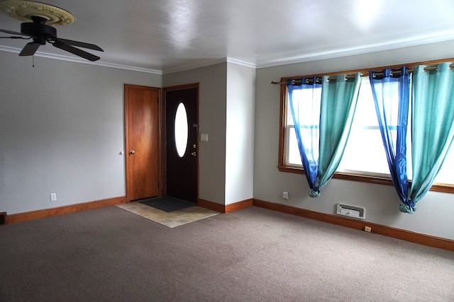 foyer entrance with ornamental molding, light carpet, and ceiling fan