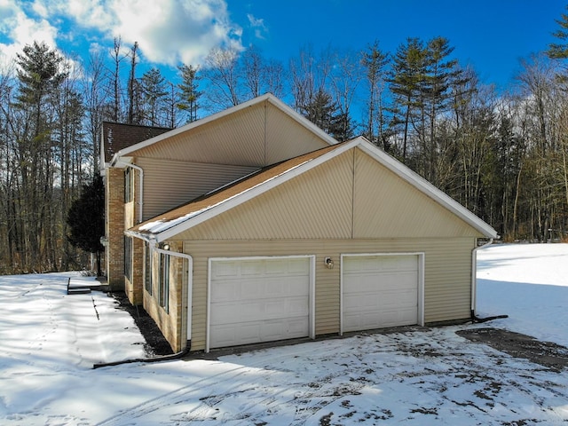 view of snowy exterior featuring a garage