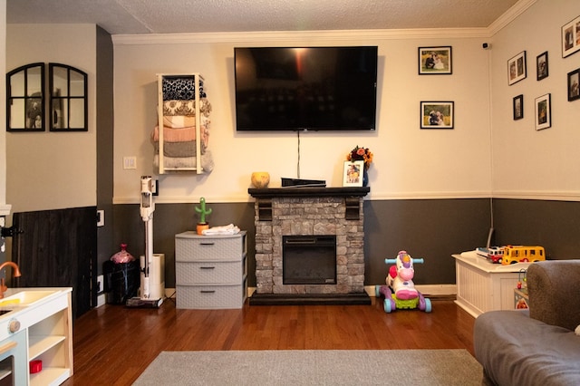 living room with crown molding, a textured ceiling, a stone fireplace, and dark hardwood / wood-style flooring