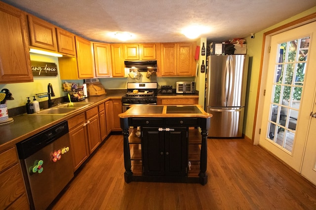 kitchen with sink, stainless steel appliances, dark wood-type flooring, and a textured ceiling