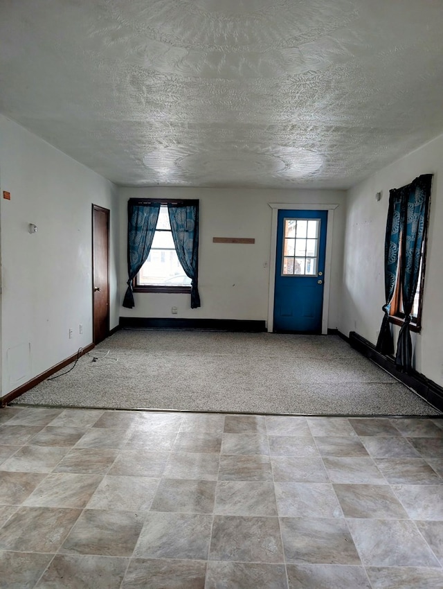 foyer entrance with light carpet, a healthy amount of sunlight, and a textured ceiling