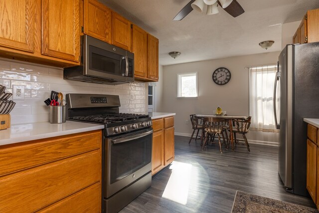 kitchen featuring dark hardwood / wood-style flooring, backsplash, ceiling fan, and appliances with stainless steel finishes