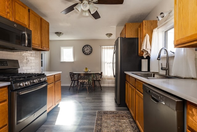 kitchen featuring dark wood-type flooring, sink, stainless steel range with gas cooktop, dishwasher, and backsplash