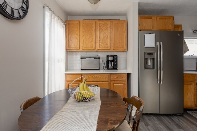 kitchen featuring stainless steel refrigerator with ice dispenser, dark hardwood / wood-style floors, a wealth of natural light, and backsplash