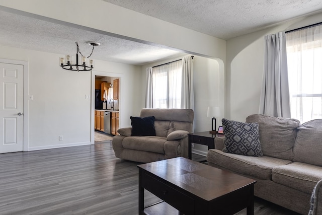 living room with an inviting chandelier, dark hardwood / wood-style floors, sink, and a textured ceiling