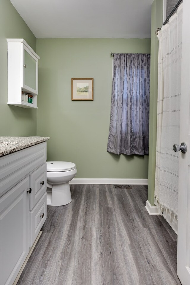 bathroom with hardwood / wood-style flooring, vanity, toilet, and a shower with curtain