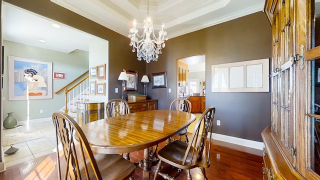 dining area with crown molding, wood-type flooring, a tray ceiling, and a chandelier