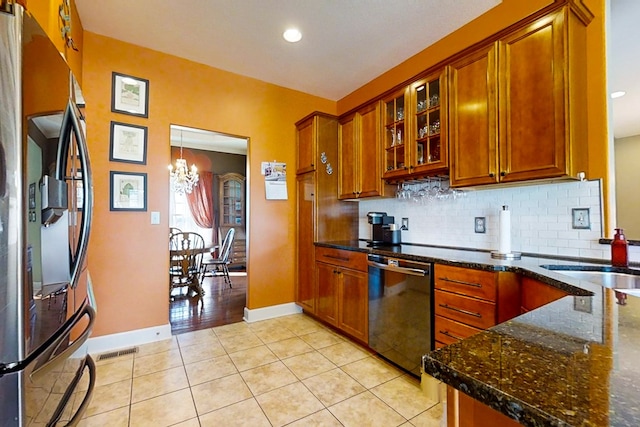 kitchen with sink, stainless steel fridge, black dishwasher, light tile patterned flooring, and dark stone counters