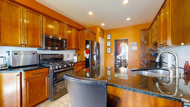 kitchen featuring appliances with stainless steel finishes, tasteful backsplash, sink, dark stone countertops, and light tile patterned floors