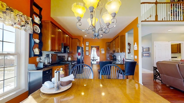 dining area featuring dark wood-type flooring, sink, and a notable chandelier