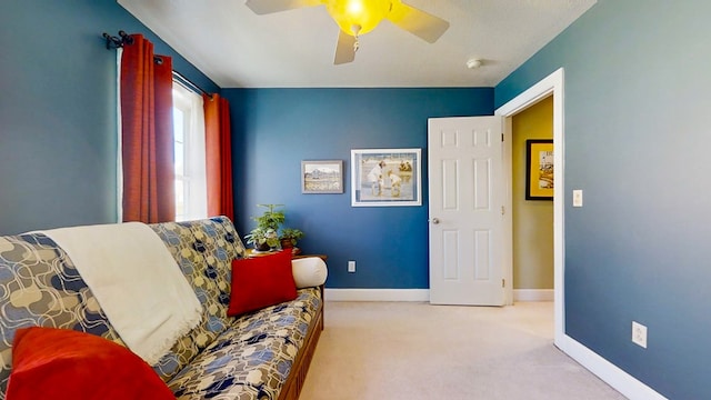 living area featuring light colored carpet and ceiling fan