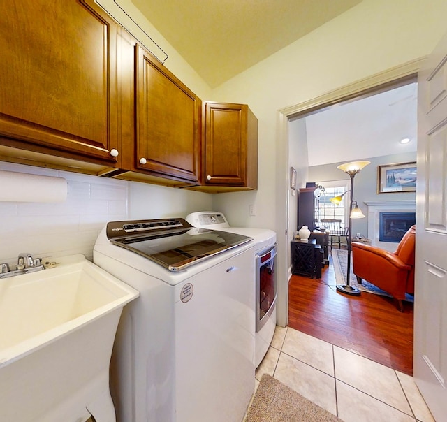 laundry area featuring cabinets, sink, light tile patterned floors, and independent washer and dryer