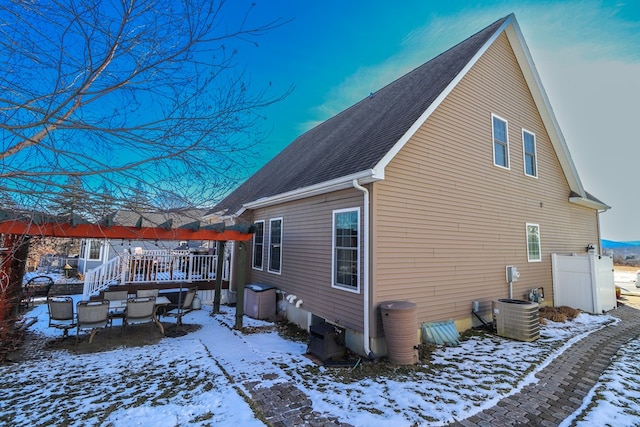 snow covered property with central air condition unit and a deck