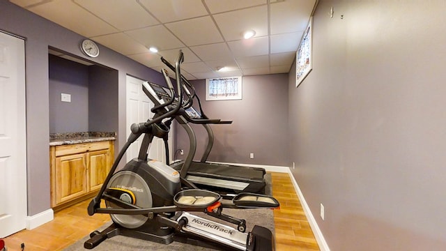 workout area featuring a drop ceiling and light hardwood / wood-style floors