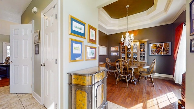 dining area featuring light tile patterned flooring, a tray ceiling, a chandelier, and crown molding