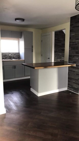 kitchen with sink, dark hardwood / wood-style floors, tasteful backsplash, a kitchen bar, and kitchen peninsula