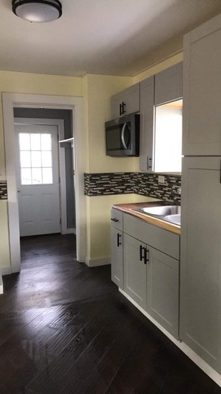 kitchen with white cabinetry, sink, dark wood-type flooring, and backsplash