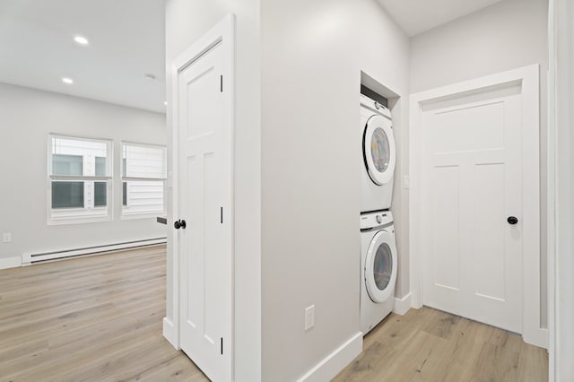 washroom with stacked washing maching and dryer, a baseboard heating unit, and light wood-type flooring