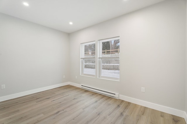 unfurnished room with a baseboard heating unit and light wood-type flooring