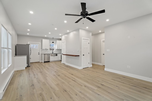 unfurnished living room featuring ceiling fan, a baseboard radiator, sink, and light hardwood / wood-style floors