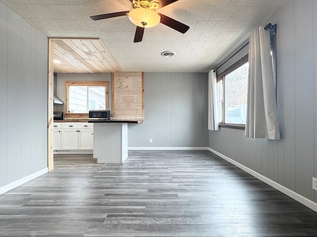 unfurnished living room with dark wood-type flooring and ceiling fan