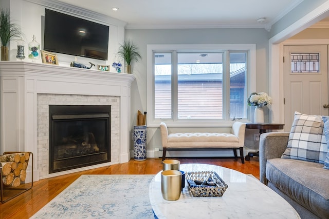 living room with crown molding, a baseboard heating unit, a fireplace, and light hardwood / wood-style floors