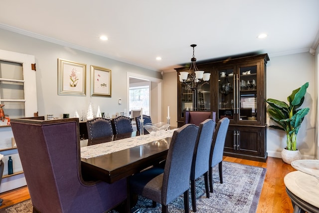 dining area featuring crown molding, light hardwood / wood-style flooring, and a chandelier