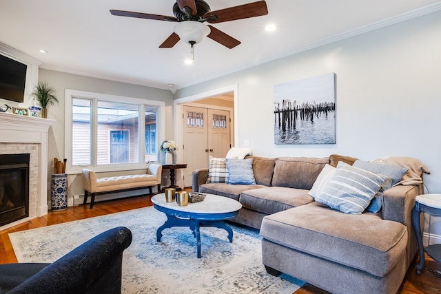 living room featuring dark hardwood / wood-style flooring, crown molding, a baseboard radiator, and a tiled fireplace