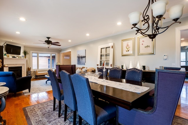 dining room with crown molding, dark wood-type flooring, and ceiling fan with notable chandelier