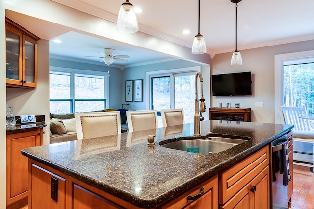 kitchen featuring crown molding, a kitchen island with sink, sink, and stainless steel dishwasher