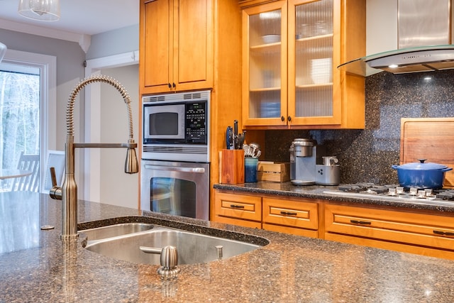 kitchen featuring stainless steel appliances, extractor fan, tasteful backsplash, and dark stone counters