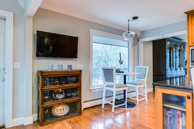 dining space featuring ornamental molding, light hardwood / wood-style floors, and a baseboard heating unit