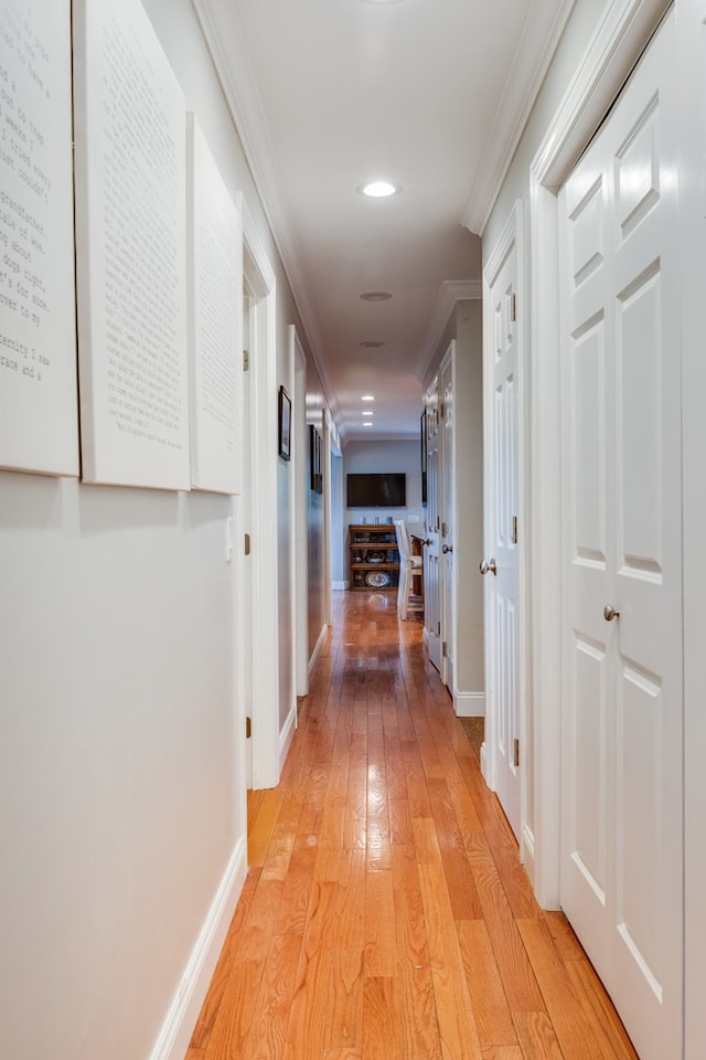 hallway featuring crown molding and light hardwood / wood-style flooring