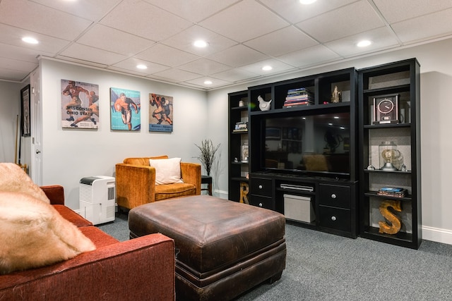 living room with dark colored carpet, a paneled ceiling, and built in features