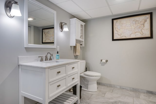 bathroom featuring vanity, toilet, and a drop ceiling