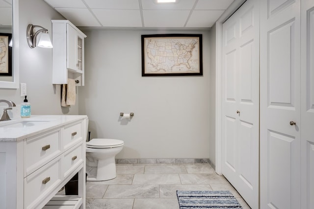 bathroom with vanity, toilet, and a drop ceiling