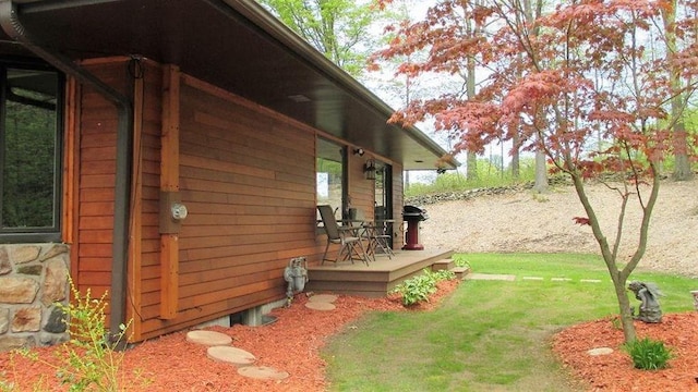 view of side of home with a wooden deck and a lawn