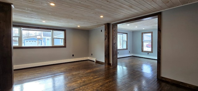 empty room featuring a baseboard heating unit, plenty of natural light, dark hardwood / wood-style floors, and wooden ceiling