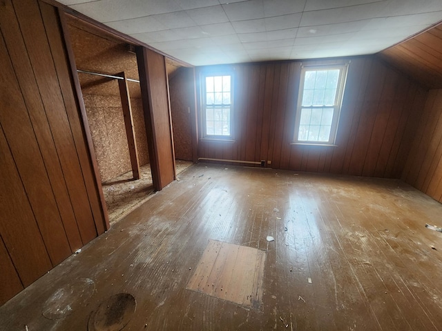 bonus room featuring vaulted ceiling, wooden walls, and light wood-type flooring