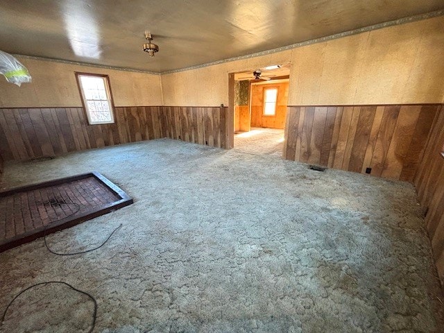 carpeted empty room featuring wood walls