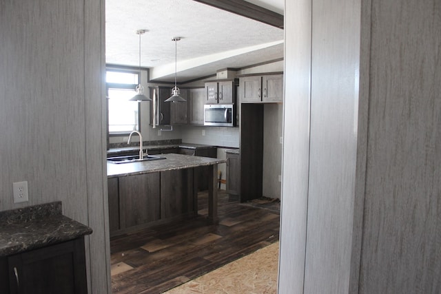 kitchen with sink, vaulted ceiling with beams, dark brown cabinets, hanging light fixtures, and dark hardwood / wood-style flooring