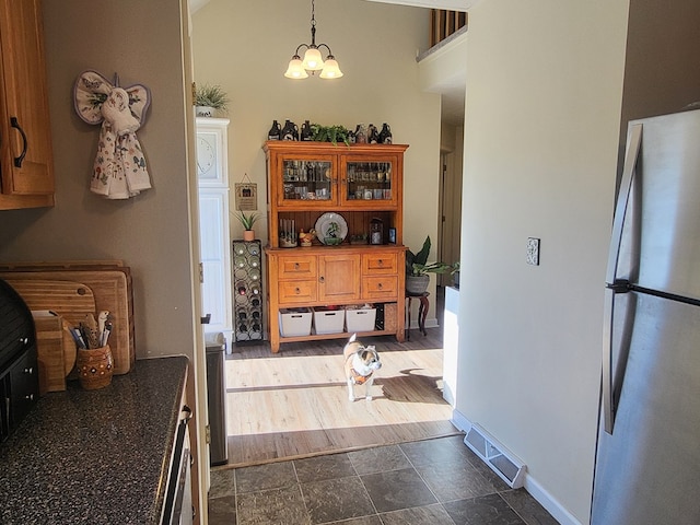 kitchen with an inviting chandelier, hanging light fixtures, and stainless steel fridge