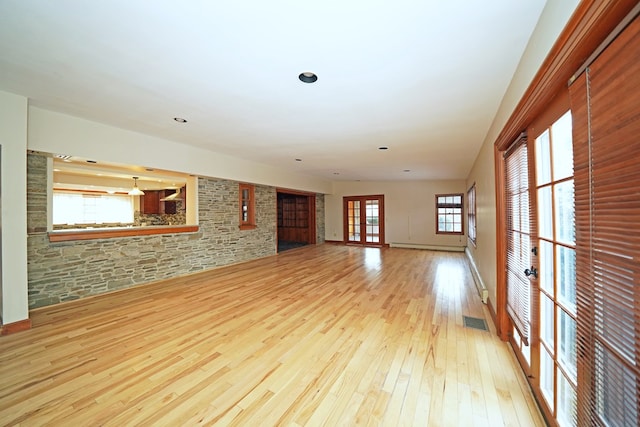 empty room with french doors, a healthy amount of sunlight, and light wood-type flooring