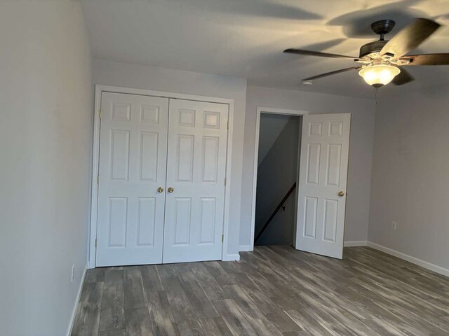 unfurnished bedroom with dark wood-type flooring, a closet, and ceiling fan