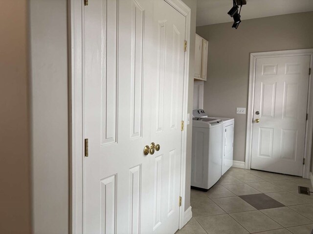 laundry area with washing machine and dryer, cabinets, and light tile patterned flooring