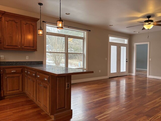 kitchen featuring decorative light fixtures, dark wood-type flooring, kitchen peninsula, and ceiling fan